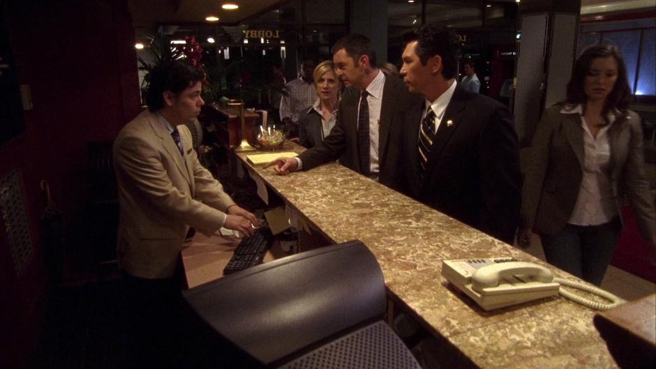 Lassiter and Ewing question the hotel clerk while Gus, Vick, and Lindsay Leikin walk up to the desk.