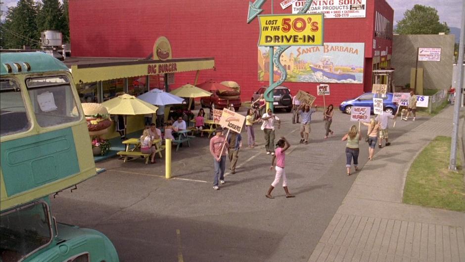 Protesters march around in front of the burger joint.