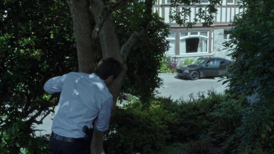 Mulder sneaks through the trees surrounding the mansion.
