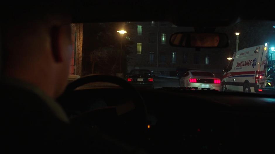 The driver follows Mulder out of the parking lot as he drives away.