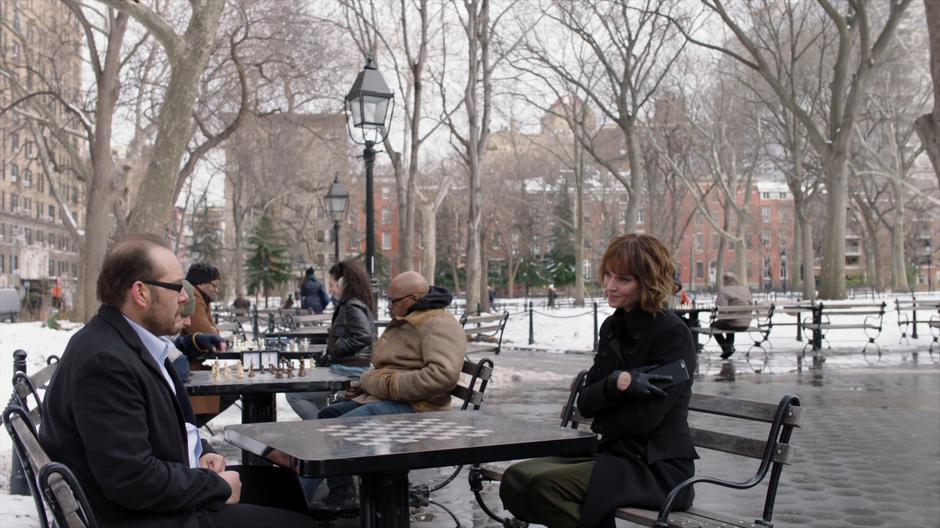 Lenny Cohen talks to the misbehaving employee after ending her phone call while the two of them sit at a chess table.