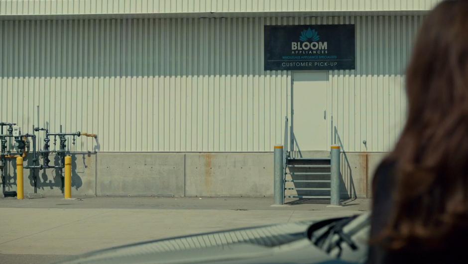Mary looks across the lot to the Bloom Appliances sign.