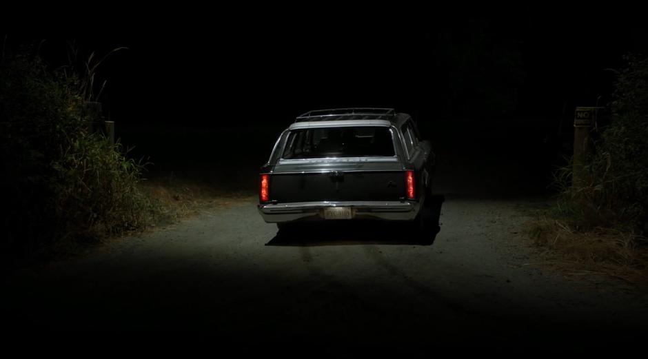 The car pulls off the road onto a dirt road leading to Mulder's place.