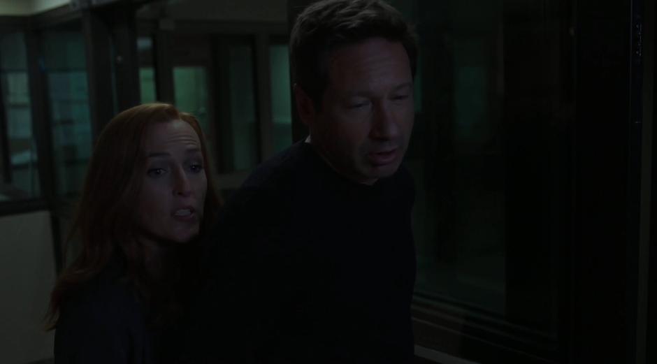 Scully approaches the guards with Mulder as a prisoner.