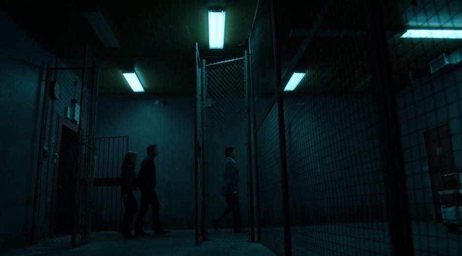 The FBI agent leads Scully and Mulder through the tunnel to the other building.