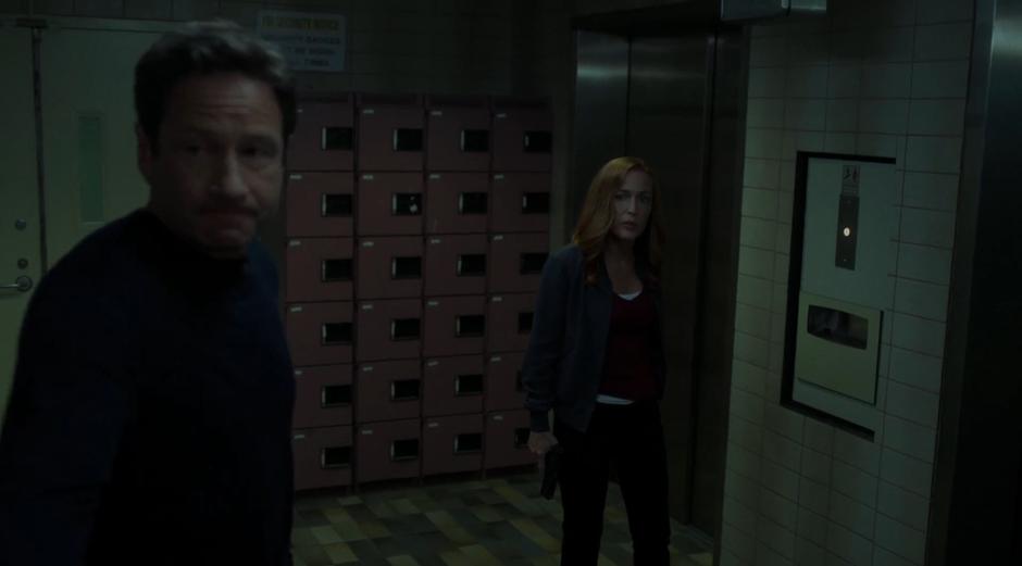 Mulder and Scully look towards the stairs that they will have to walk up.