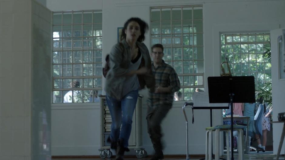Kady and Josh run away from the window towards the exit.