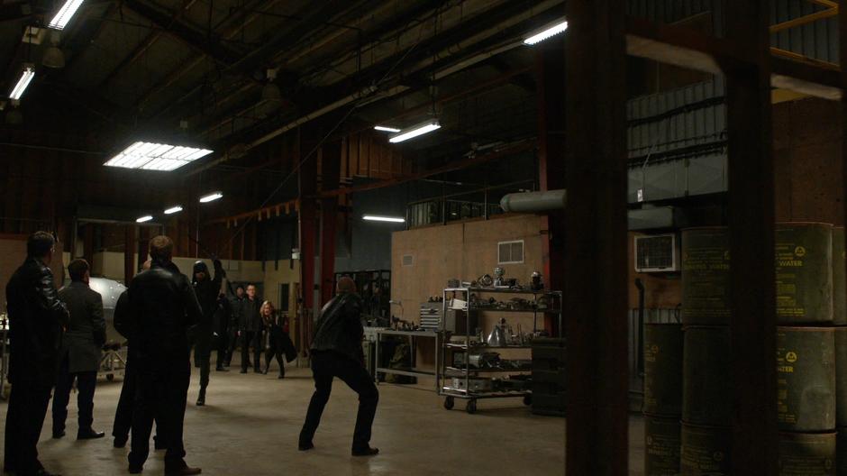 Oliver fires a grappling arrow into the ceiling to escape the goons.
