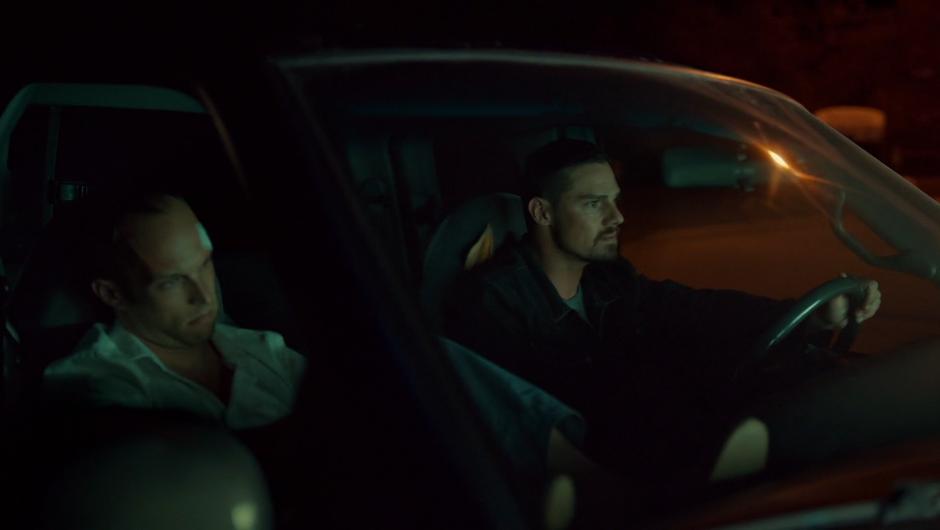 Ben drives down the street with Travis Bloom handcuffed in the passenger seat.
