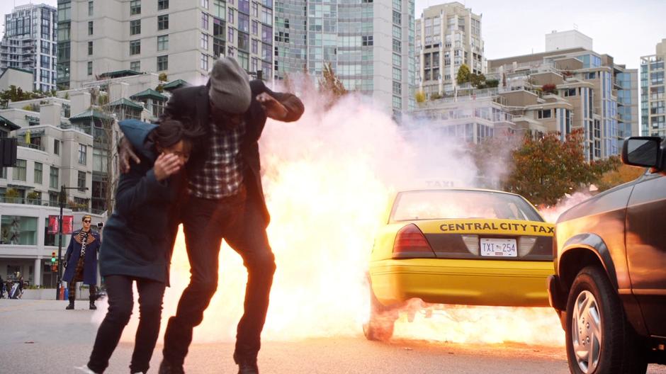 Axel Walker films while the taxi explodes and the two people run for cover.