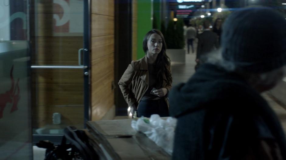 Julia walks out of the store and notices the homeless woman outside.