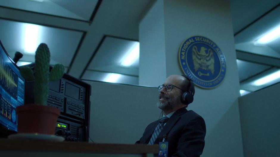 Reggie laughs while listening to a conversation between Scully and Mulder while working at the NSA.