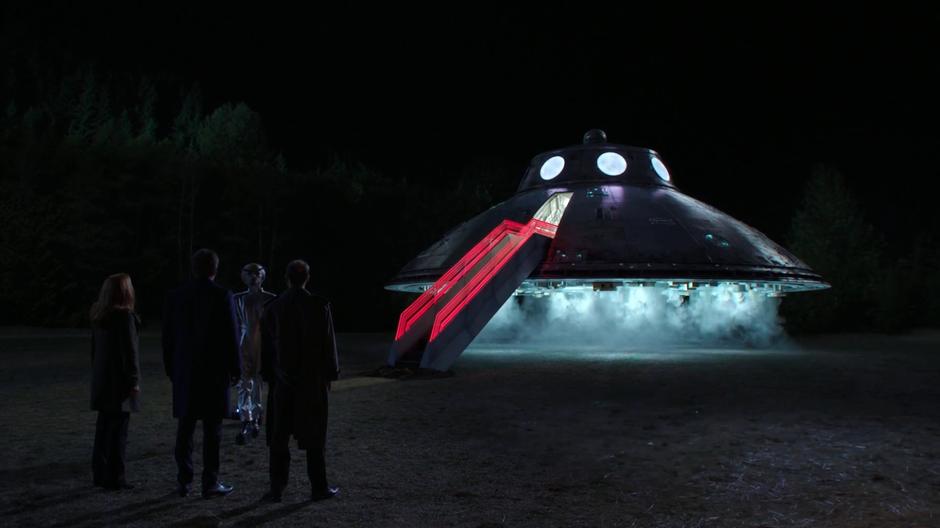 The alien rolls over to Scully, Mulder, and Reggie from his hovering spaceship.