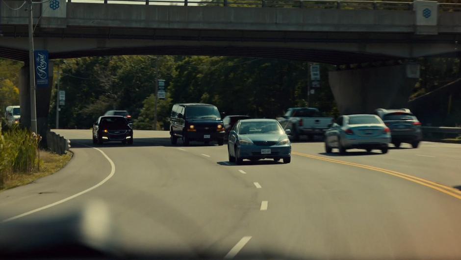 A black van drives down the highway behind Mary.