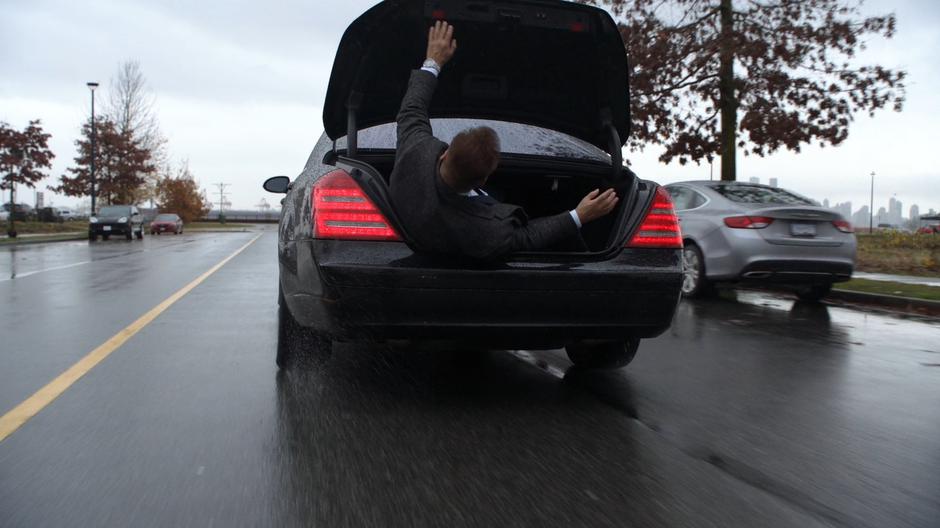 Edge climbs out of the back of the car as it drives itself down the street.