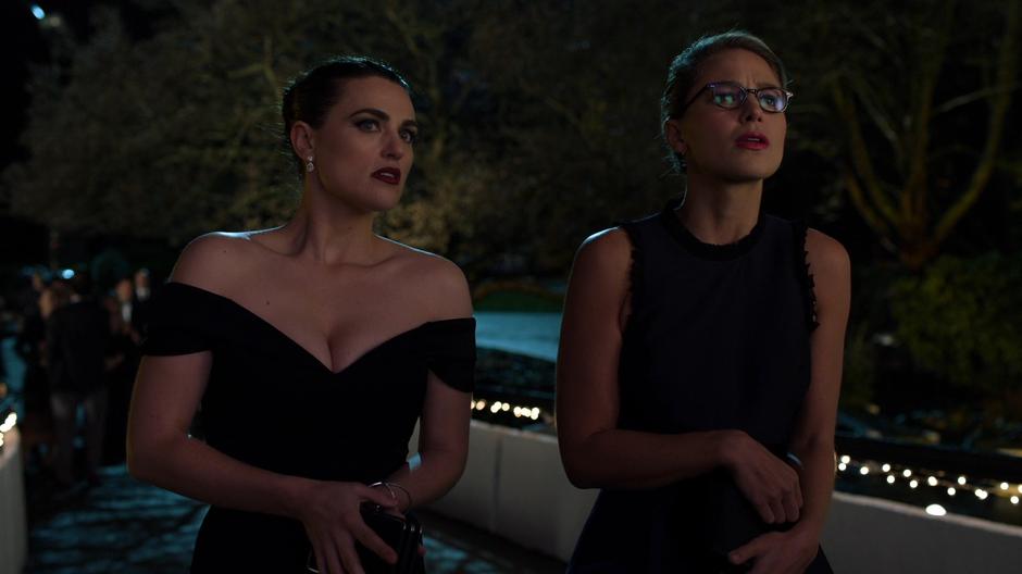 Lena and Kara look over at where Edge is flirting with some woman at the party.