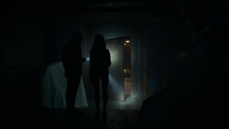 Quentin and Julia walk through the dark room to where a door has opened itself to a lit chamber.