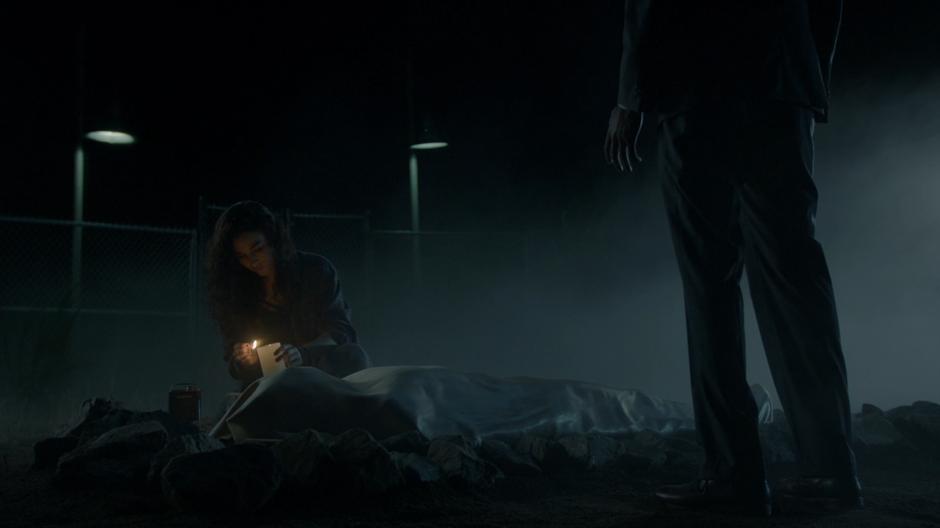 Penny watches as Kady lights a candle next to Penny's body.