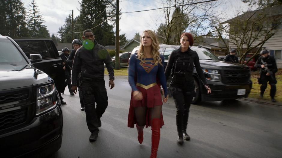 J'onn, Kara, and Alex walk to the house with the DEO team.