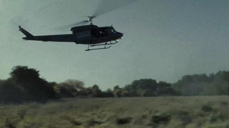 The Huey lands in the middle of the field.