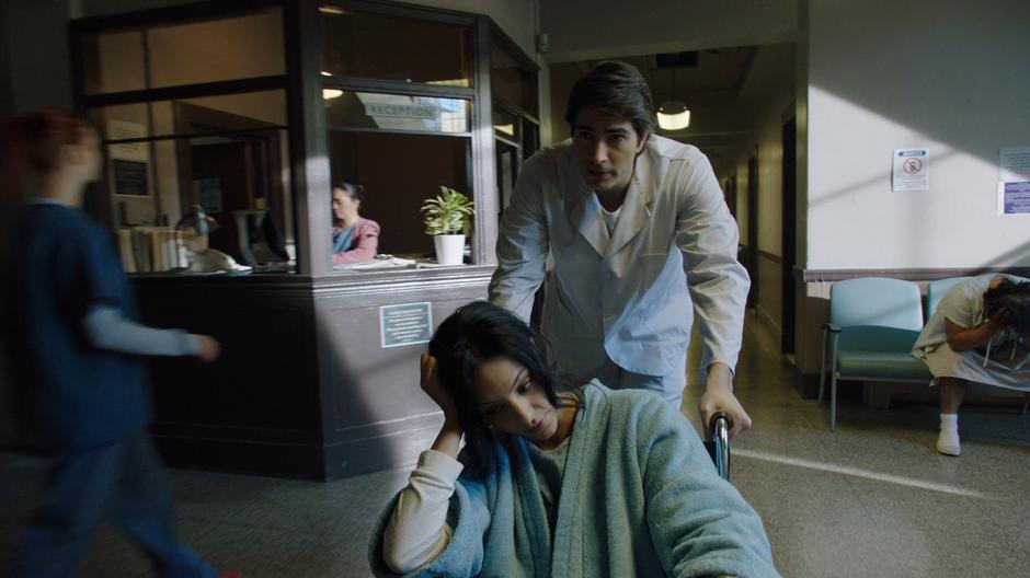 Ray pushes Zari through the lobby while disguised as a doctor and patient.