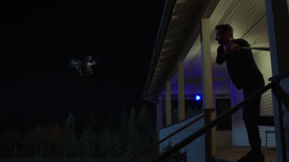 Mulder tries to hit the drone with a bat from his porch.