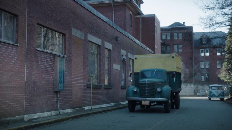 The truck drives along the back of the safe house.