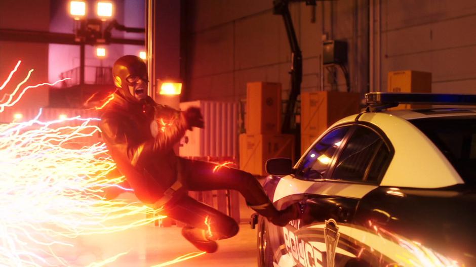 Barry runs along the side of a police car and prepares to throw the sphere.
