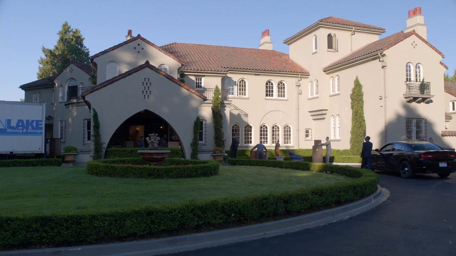 Clive and Liv exit the car and walk up to the mansion while movers carry around boxes.