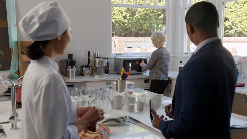 The chef and Clive look over at Liv who is messing with the microwave to head up a drink.