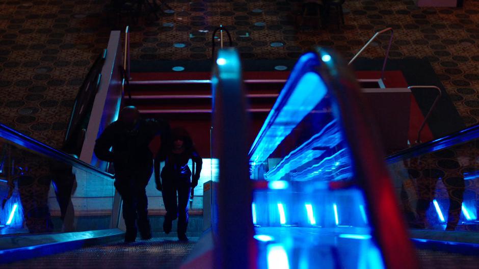 Diggle and Thea run up the escalator.