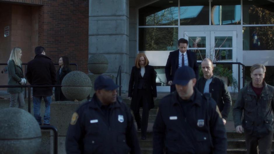 Scully and Mulder walk down the steps of the courthouse as everyone else leaves.