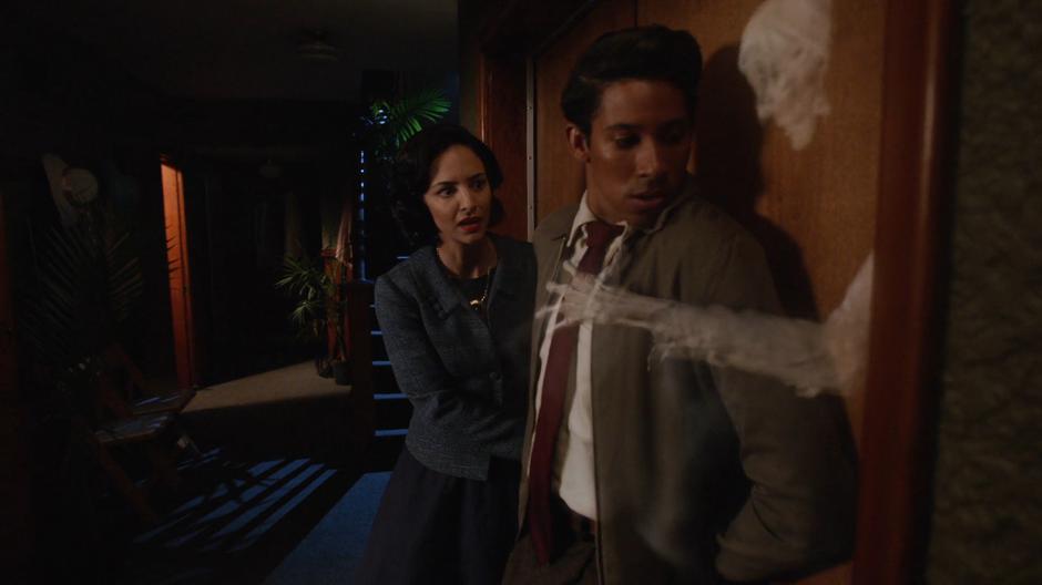 Zari and Wally watch as a ghost reaches through the door and grabs at Wally.