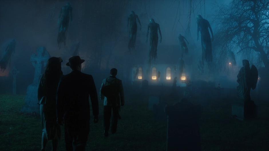 Amaya, Nate, and Elvis walk through the graveyard while spirits hover overhead.