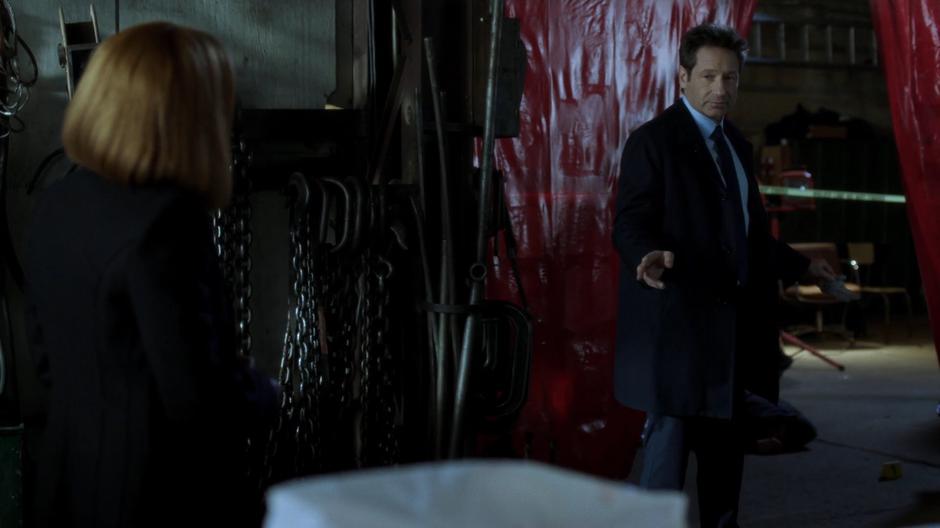 Scully watches as Mulder looks around the crime scene.