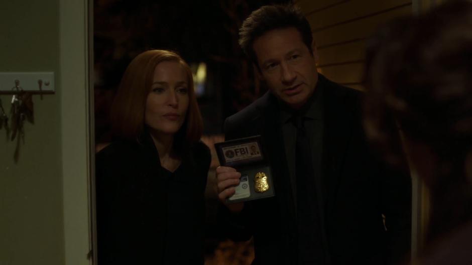 Mulder shows his FBI badge while identify himself and Scully to Josephine Bocanegra at the door.