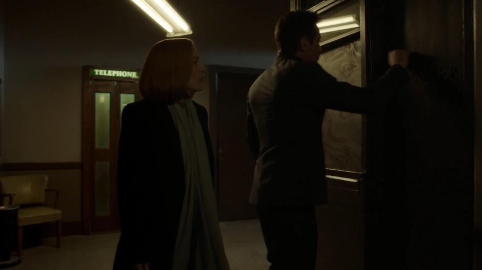 Mulder knocks on the landlord's apartment with Scully.