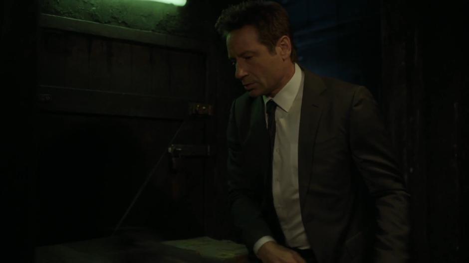 Mulder clears debris from in front of the elevator door.