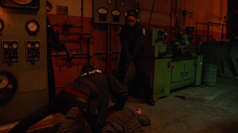 Clive tackles Bruce Holtz to the ground while Officer Michelle covers him with her gun.
