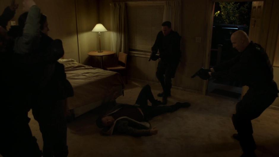 Two soldiers point their guns at Mulder on the floor while a third holds William.