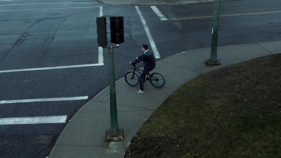William waits on the sidewalk at the corner on his bike.