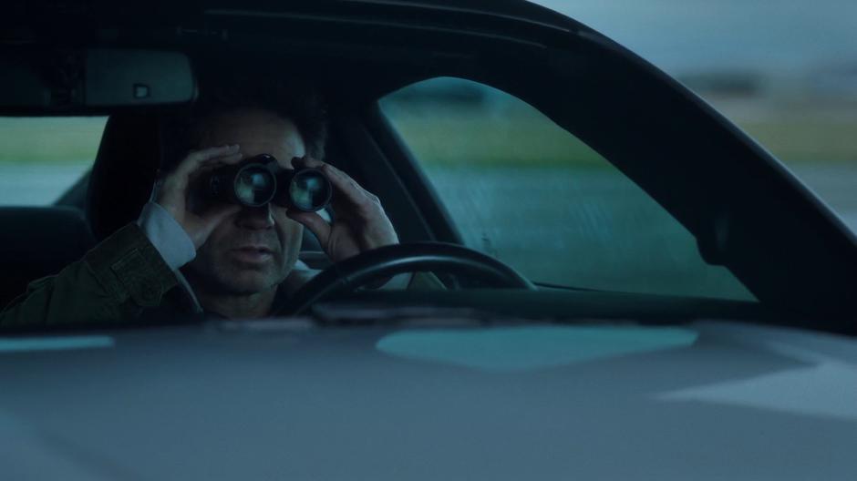 Mulder watches the plane through binoculars.
