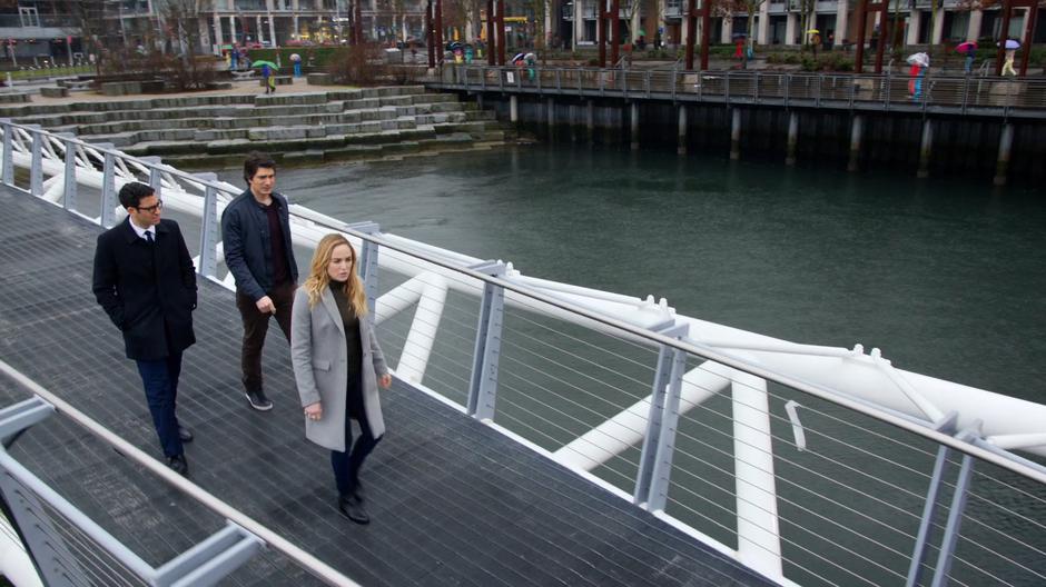 Gary, Ray, and Sara walk across a pedestrian bridge in futuristic Vancouver.