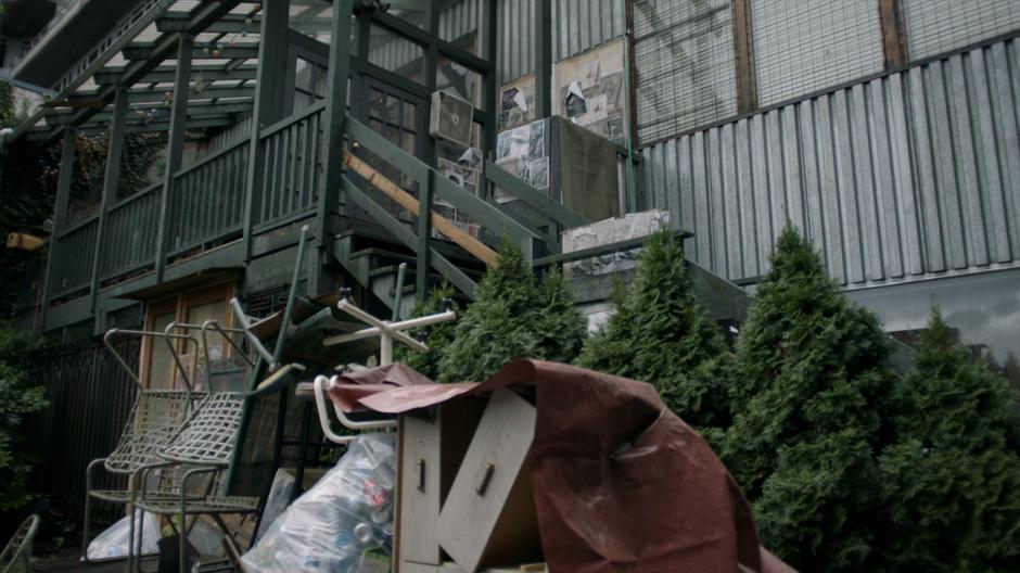 Establishing shot outside Reynard's apartment covered in junk.