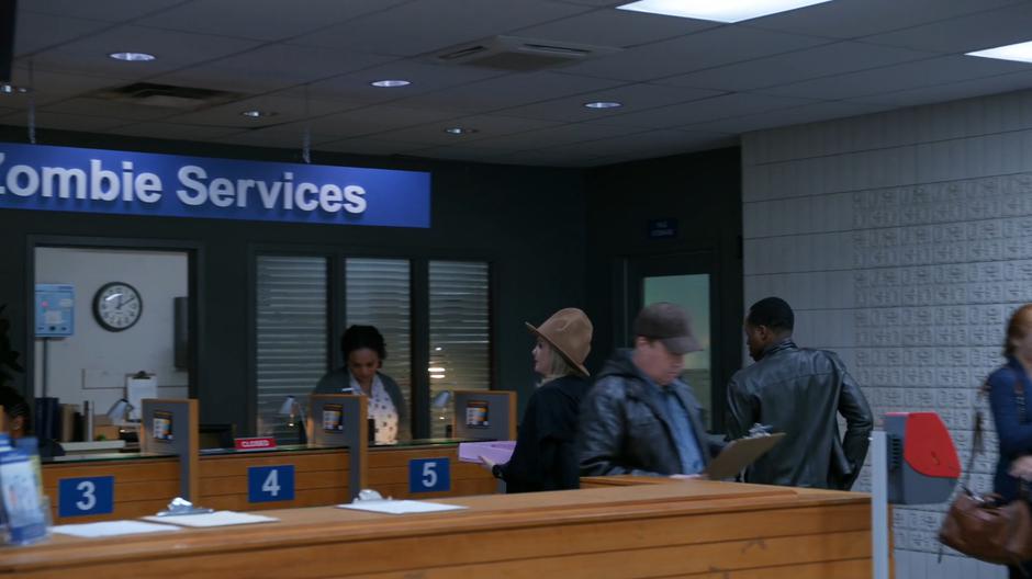 Liv and Clive walk up to the woman at the desk.