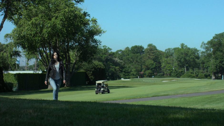 Jessica strides across the hills of the golf course towards Justis Ambrose.