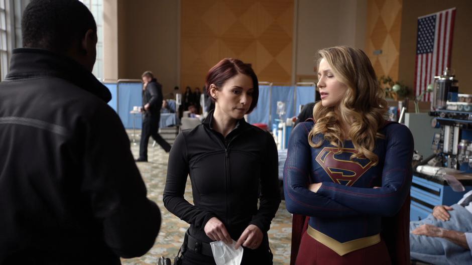 Alex and Kara talk with J'onn as DEO agents look after the employees.