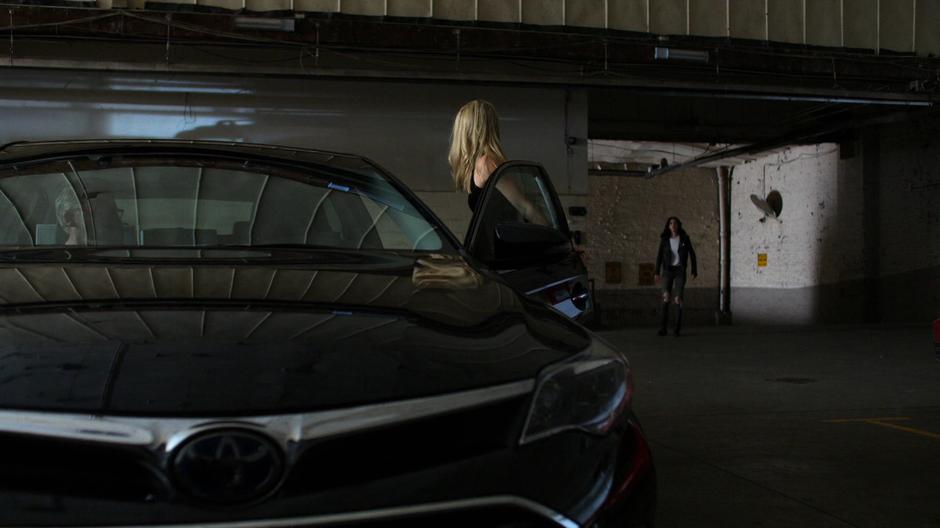 Trish turns as she is getting into the car to look over at Jessica.