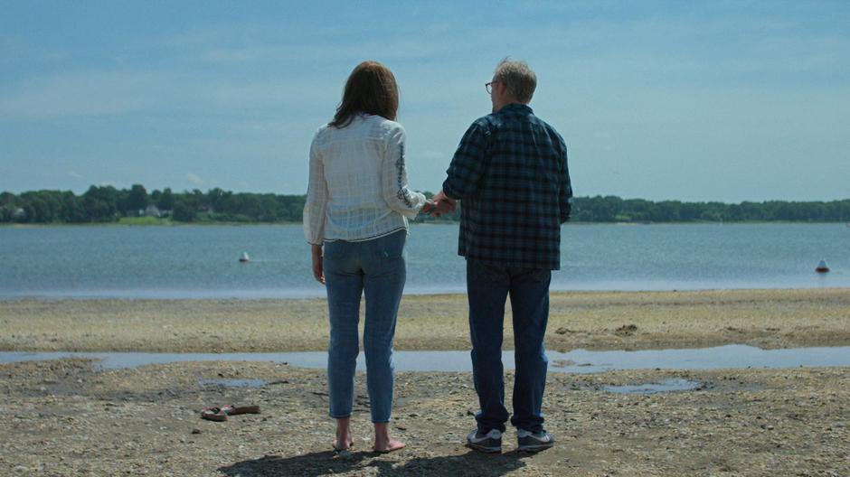 Alisa and Malus hold hands while looking out at the water.