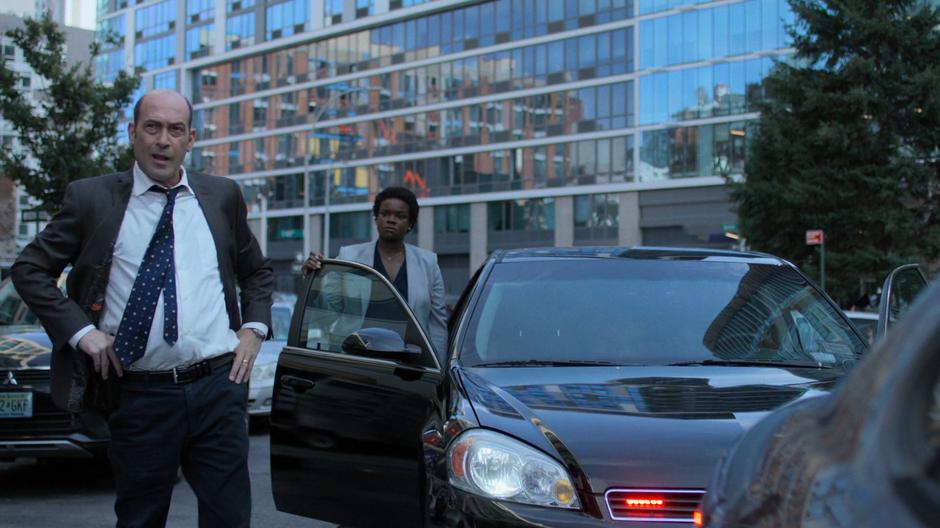 Detectives Costa and Sunday stand beside the car and watch as Jessica runs towards the hospital.